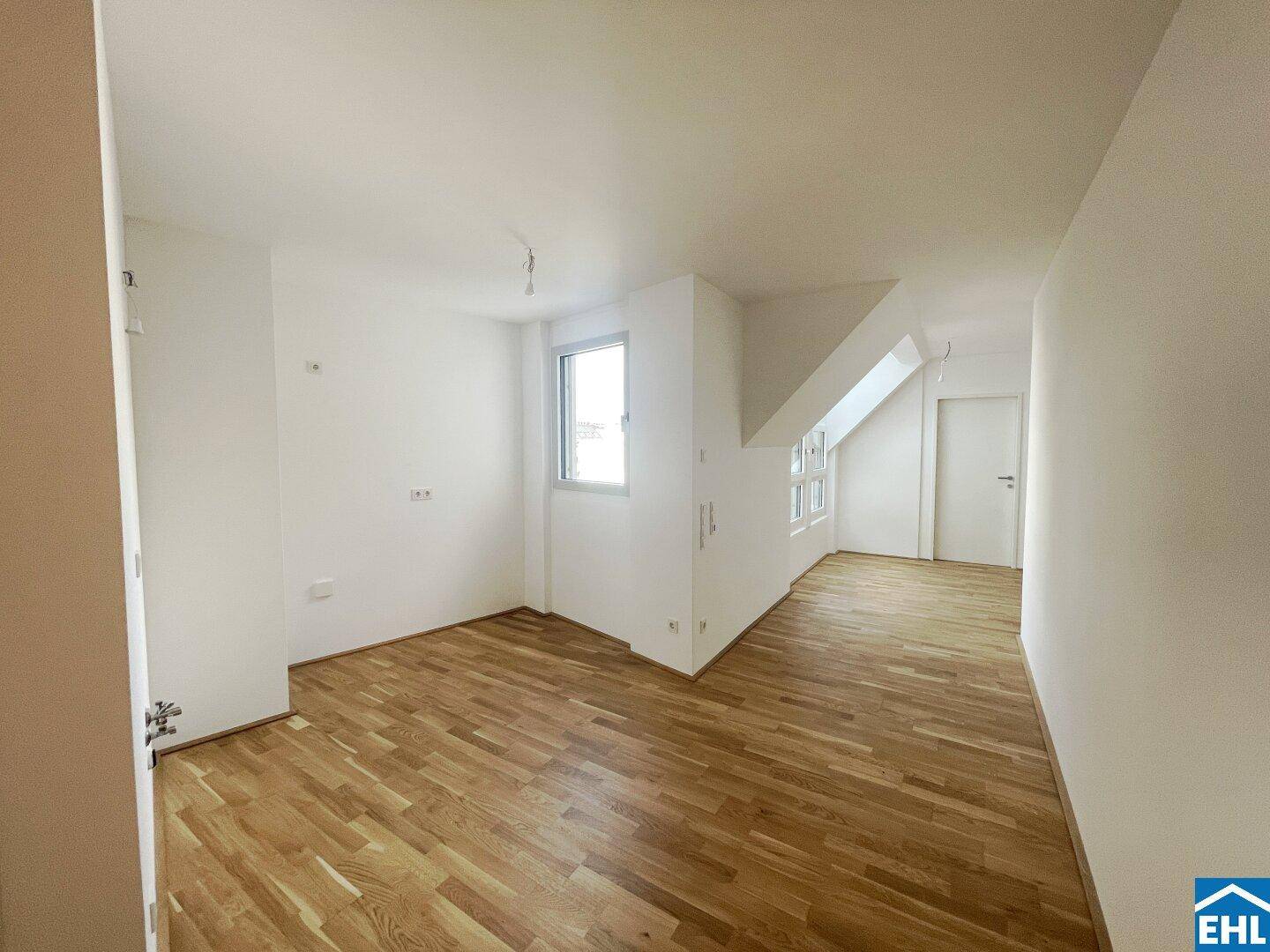 Heller Raum mit Holzboden, weißen Wänden und einem Fenster, ideal für flexible Nutzung.