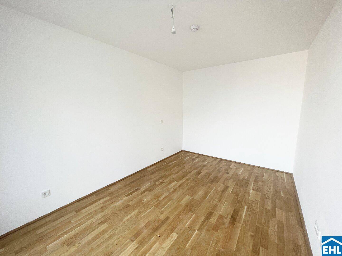 Schlichtes, leeres Zimmer mit hellem Parkettboden und weißen Wänden, bereit zur individuellen Gestaltung.