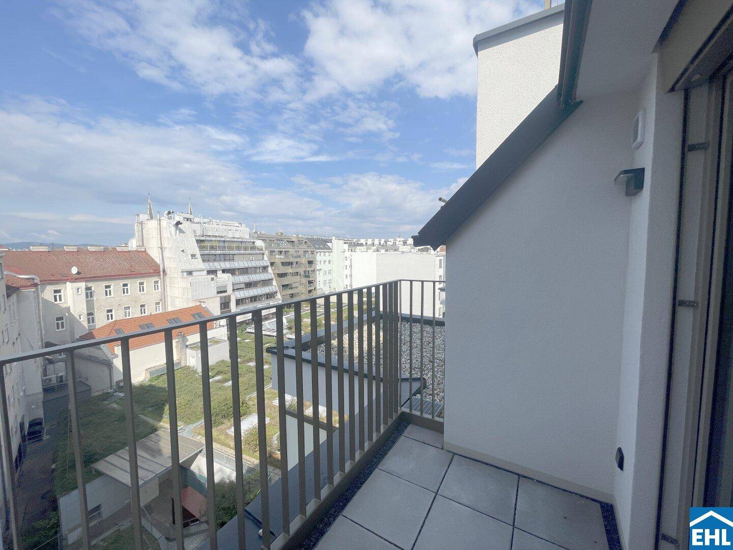 Balkon mit Fliesenboden und weitem Blick über die städtische Skyline und umliegende Gebäude.