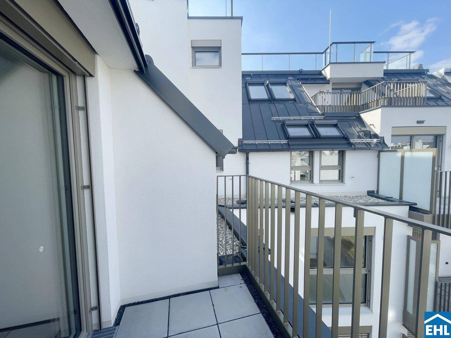 Balkon mit Blick auf die moderne Gebäudefassade und weitere Balkone sowie Dachfenster.