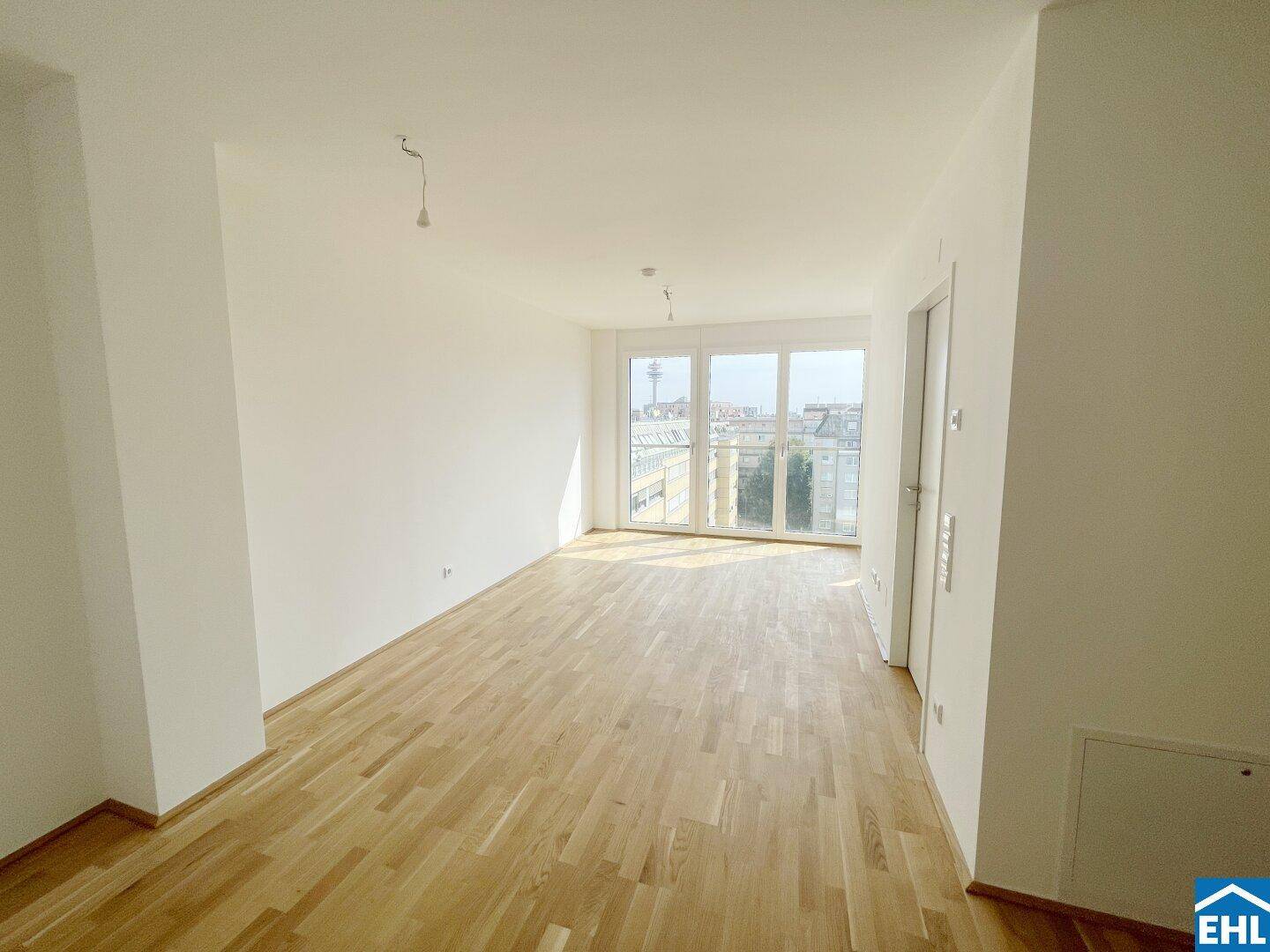 Helles, leeres Zimmer mit Parkettboden und Zugang zu einem Balkon, ideal für Wohn- oder Essbereich.