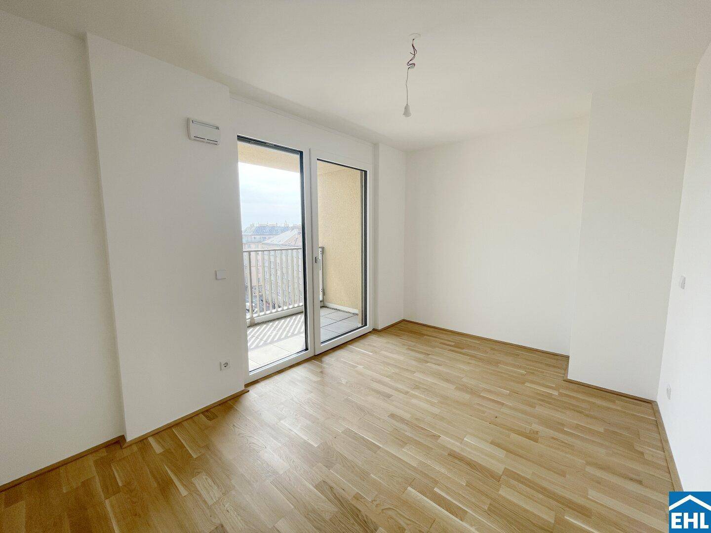 Heller Raum mit Parkettboden und direktem Zugang zu einem Balkon, ideal als Schlafzimmer.