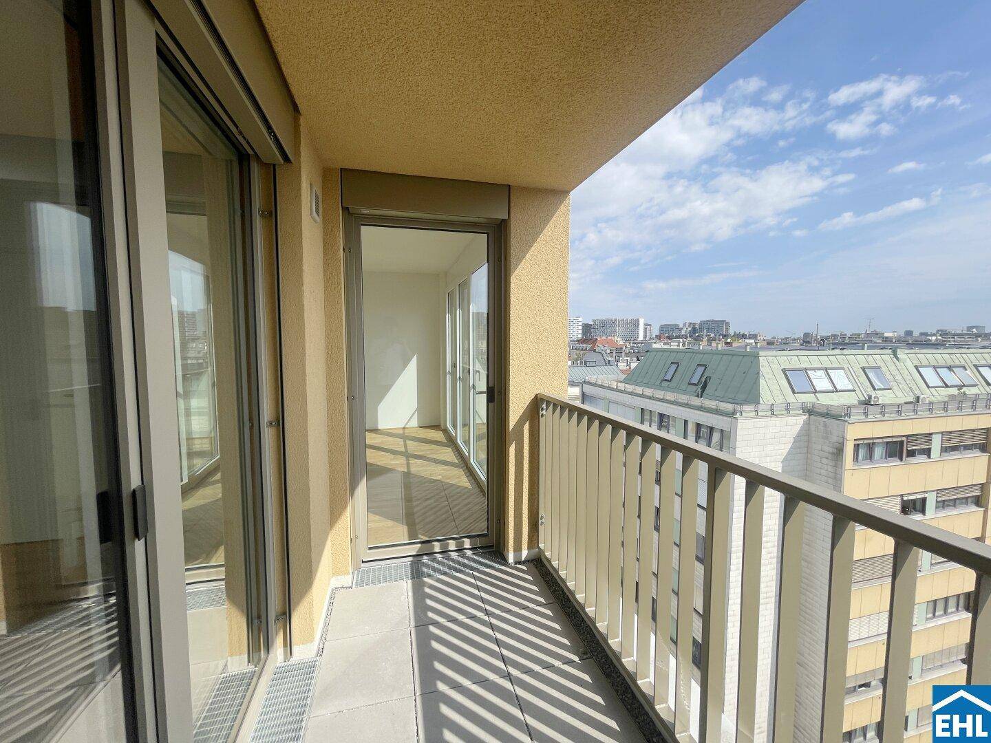 Geräumiger Balkon mit Blick auf die Stadt, zugänglich durch große Glasfenster.