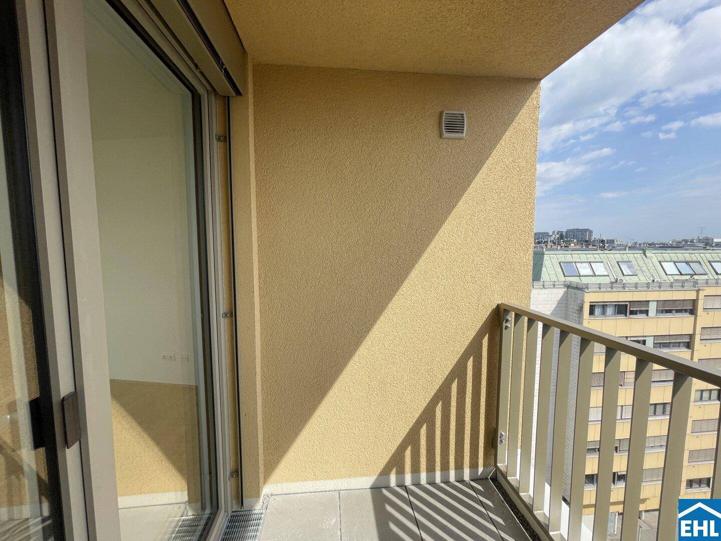 Geräumiger Balkon mit gelber Wand und weitem Blick über die Dächer der Stadt.
