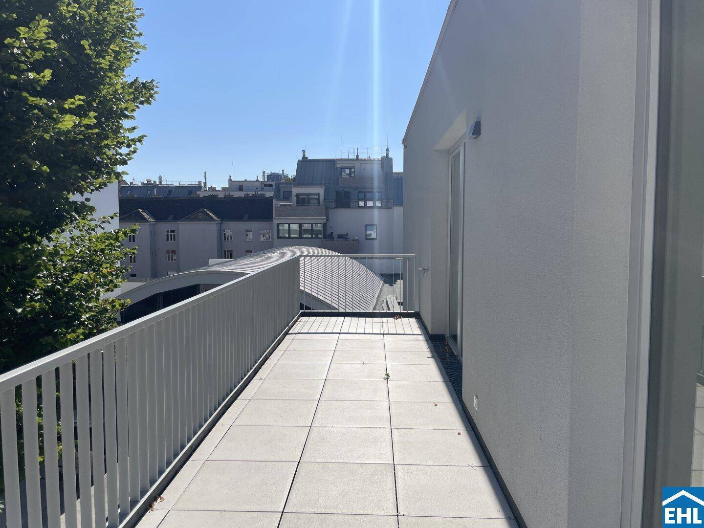 Langer, sonniger Balkon mit Fliesenboden und weitem Blick über die Stadt.