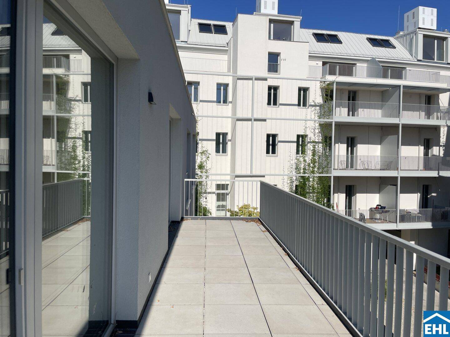 Heller Balkon mit Fliesenboden und Blick auf die moderne Architektur der Nachbargebäude.