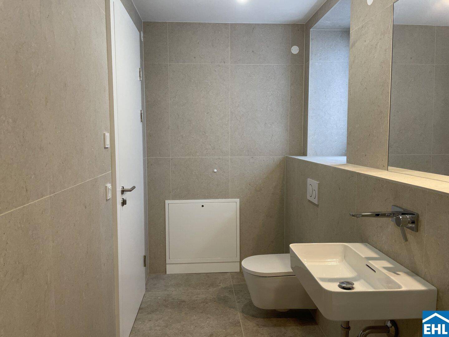 Helles Badezimmer mit modernen Fliesen, wandhängendem WC und elegantem Waschbecken.
