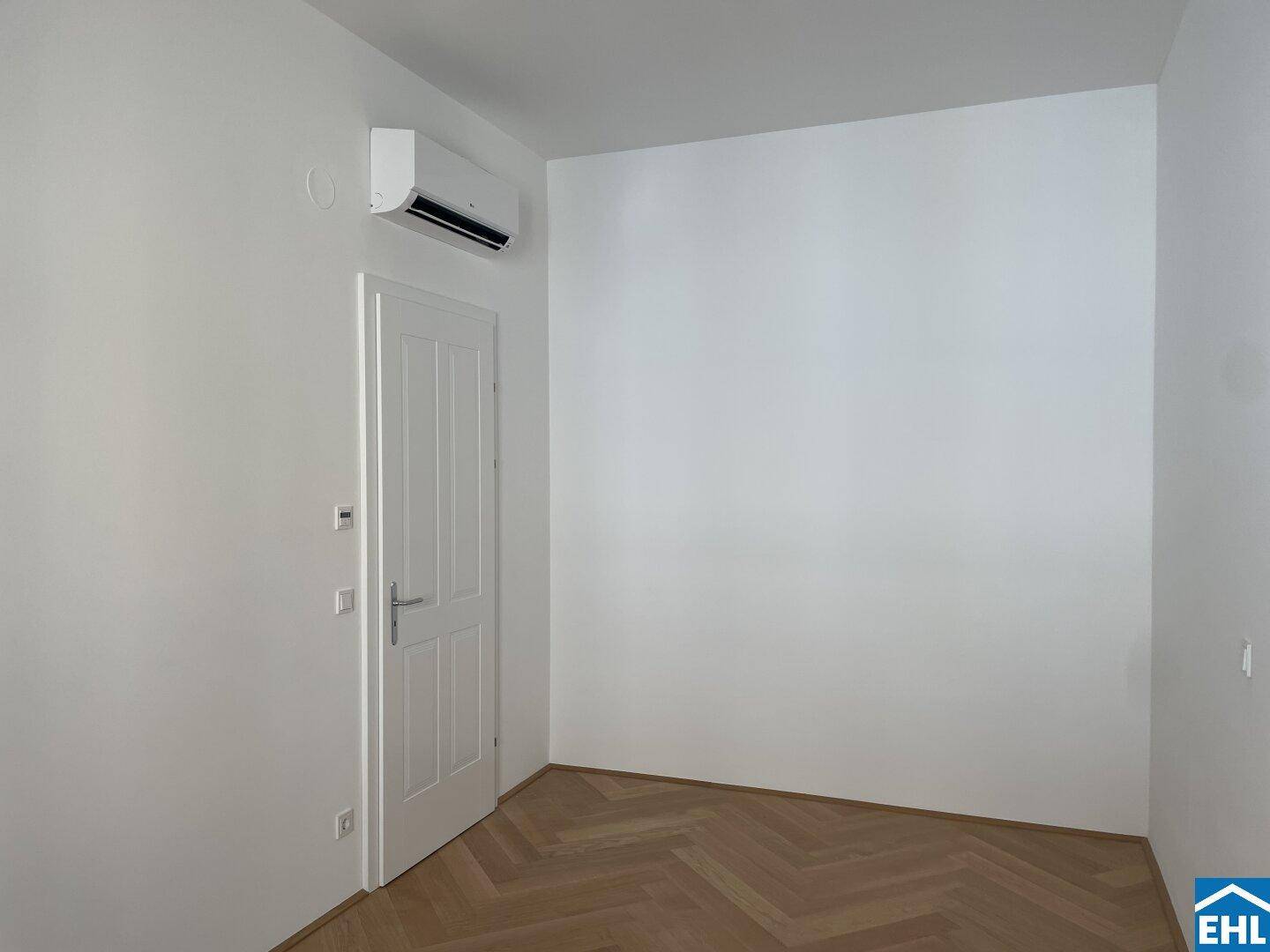 Schlafzimmer mit Klimaanlage und weißer Tür, bereit für die Einrichtung.
