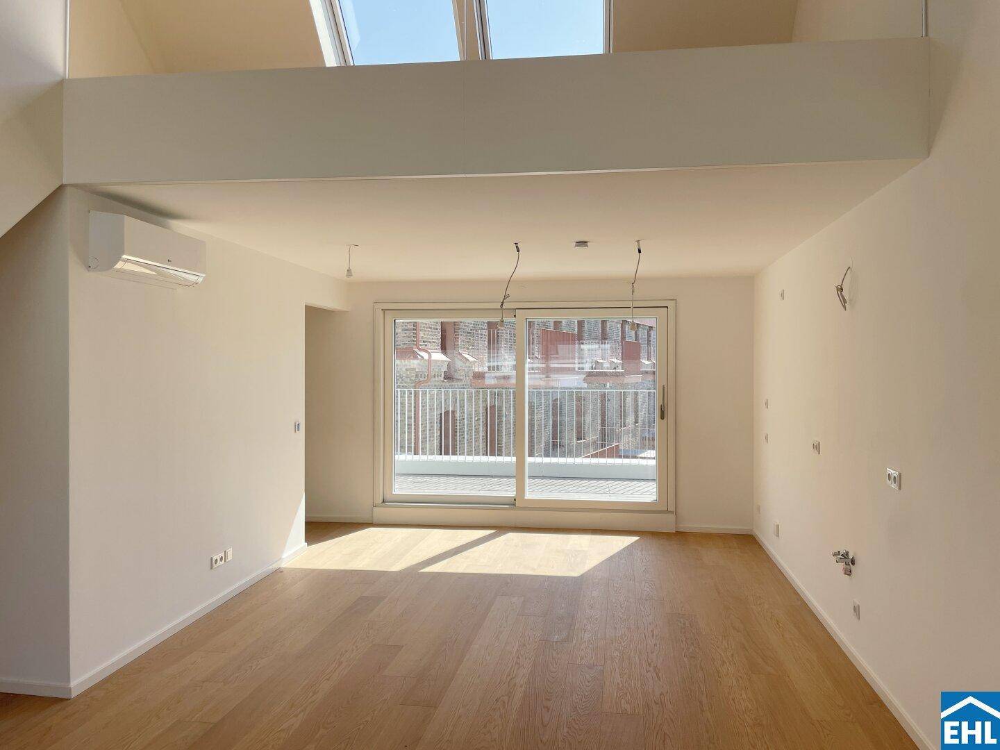 Lichtdurchfluteter Wohnraum mit Holzboden, großen Schiebetüren zur Terrasse und Klimaanlage.