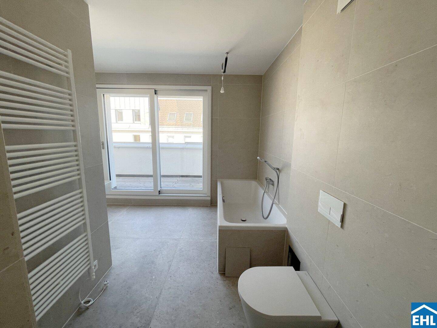 Modernes Badezimmer mit hellgrauen Fliesen, Badewanne, wandhängendem WC und Terrassenzugang.