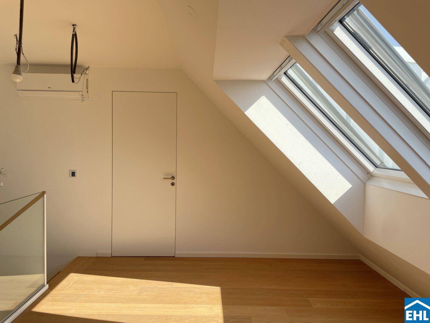 Heller Wohnbereich mit Holzboden, Dachfenstern und Klimaanlage, mit moderner Glasbrüstung.