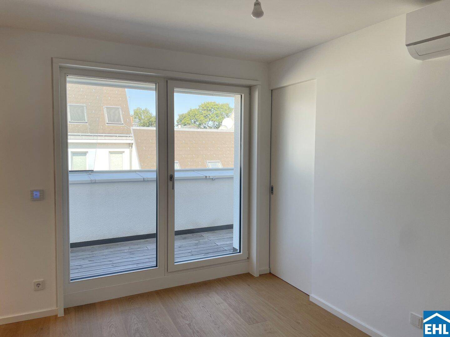 Helles Schlafzimmer mit Holzboden, Zugang zur Terrasse und Klimaanlage für angenehme Temperaturen.