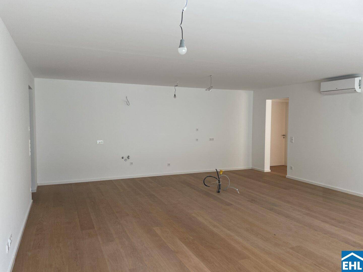 Geräumiges, unmöbliertes Wohnzimmer mit Holzparkett und Vorbereitung für Beleuchtung und Klimaanlage.