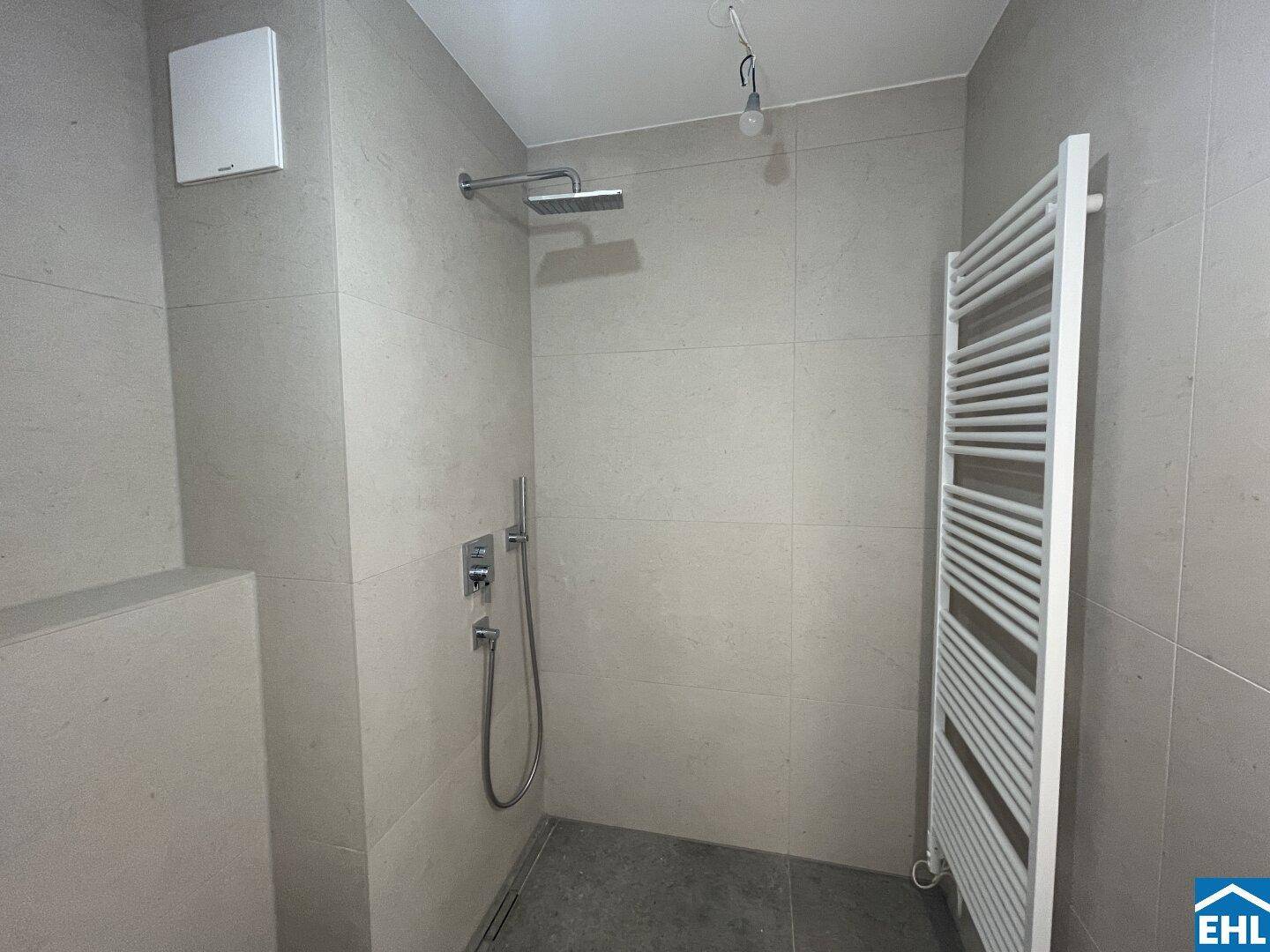 Duschbereich im modernen Badezimmer mit Regendusche, Fliesen und beheiztem Handtuchhalter.