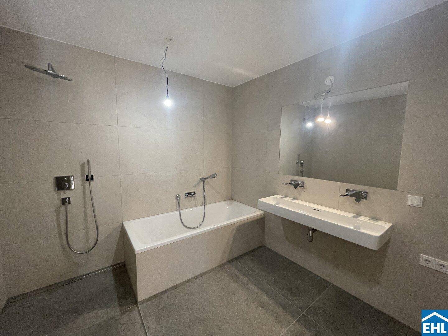 Modernes Badezimmer mit Badewanne, großem Waschbecken und eleganten Fliesen an Wänden und Boden.