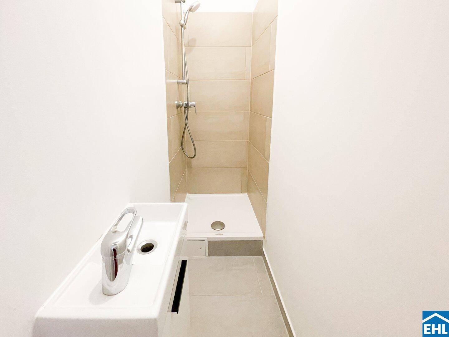 Schlichtes Badezimmer mit Duschbereich und modernem Einzelwaschbecken, funktional und hell gestaltet.