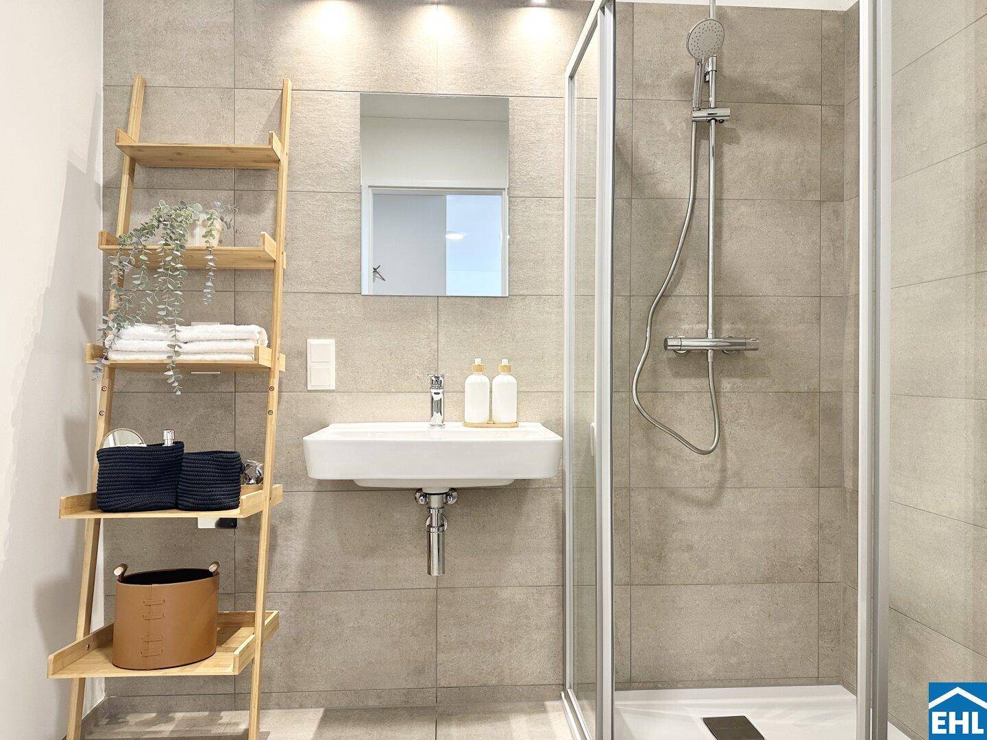 Modernes Badezimmer mit begehbarer Dusche, eleganten Fliesen und Holzregal.