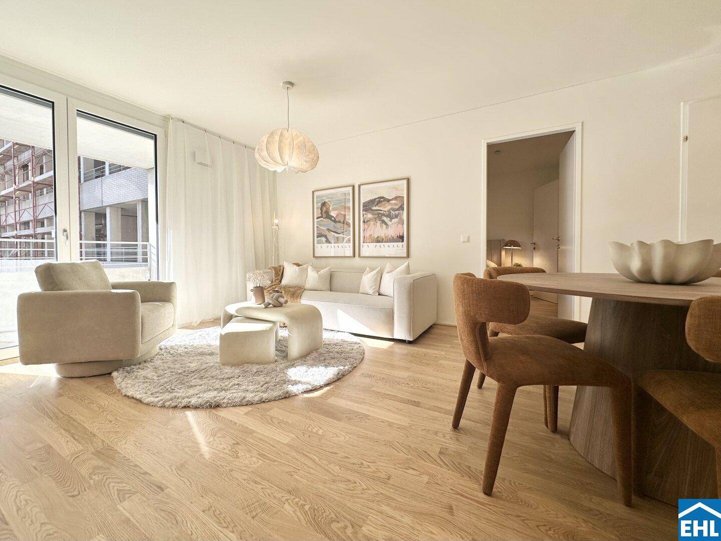 Geräumiges Wohnzimmer mit hellem Holzboden, großen Fenstern und modernem Interieur.