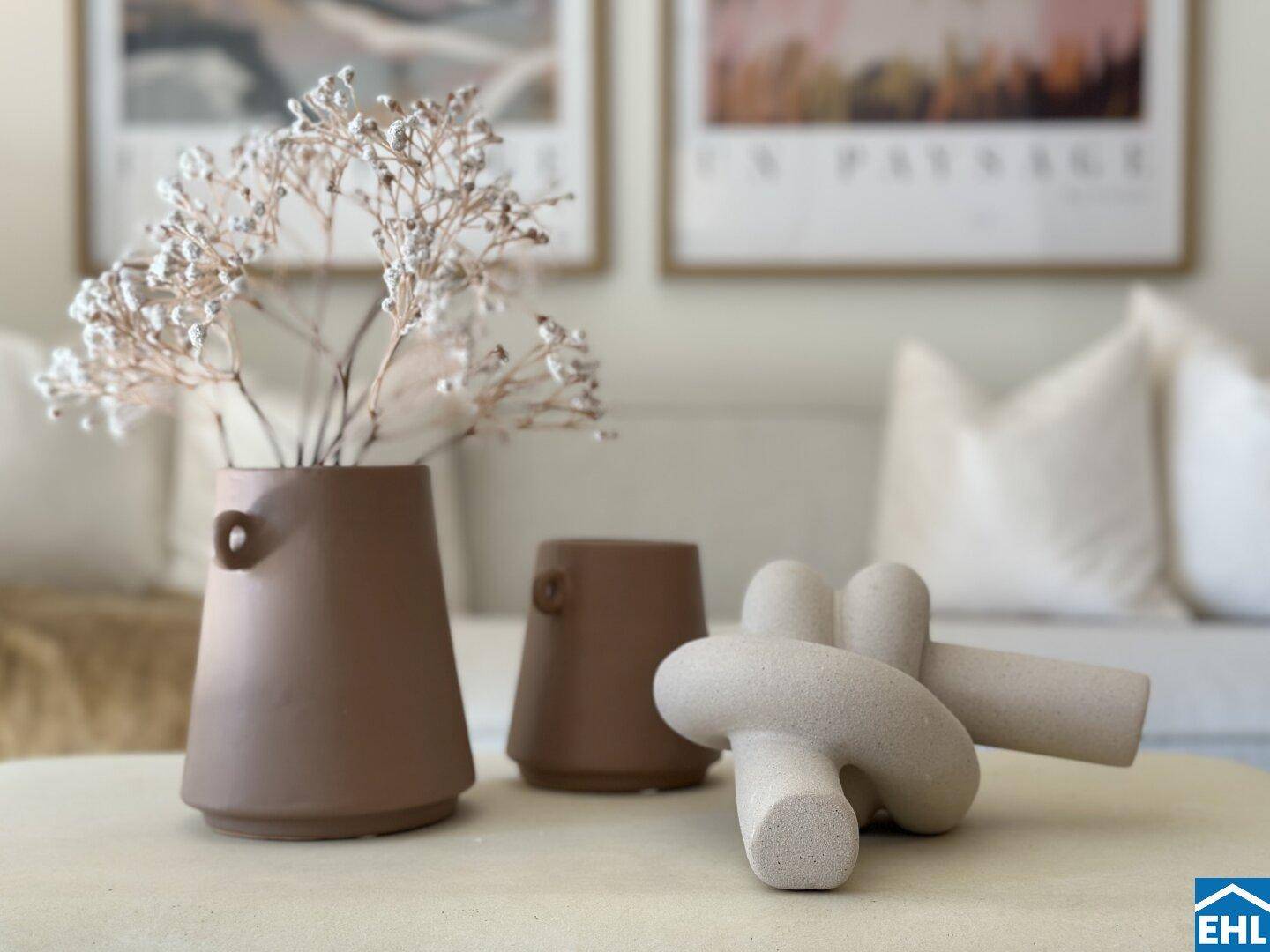 Dekorative Elemente auf einem Couchtisch im Wohnzimmer, darunter Vasen und eine Skulptur.