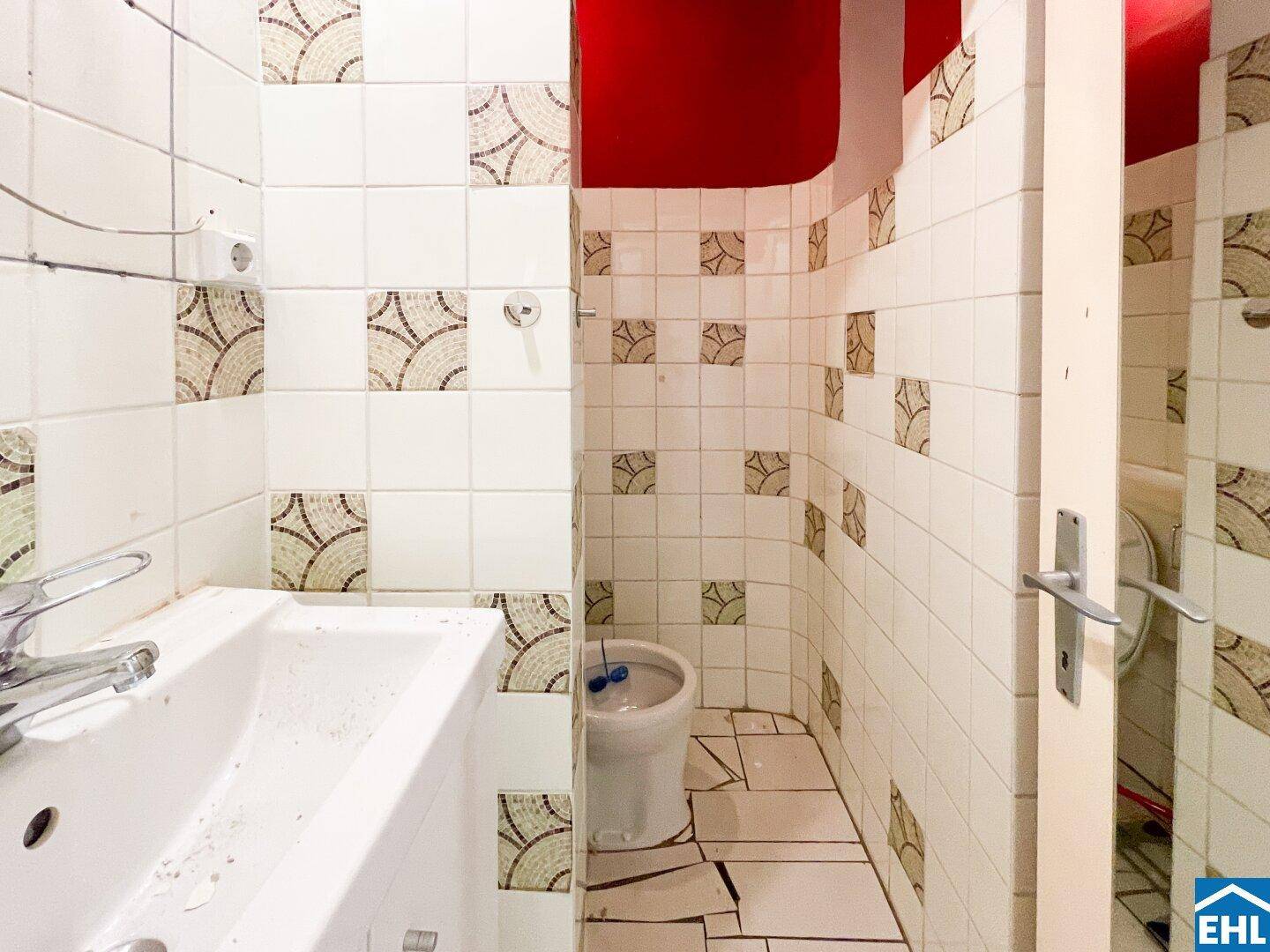 Kleines WC mit Waschbecken, Toilette und Fliesen an den Wänden in Renovierungsbedarf.