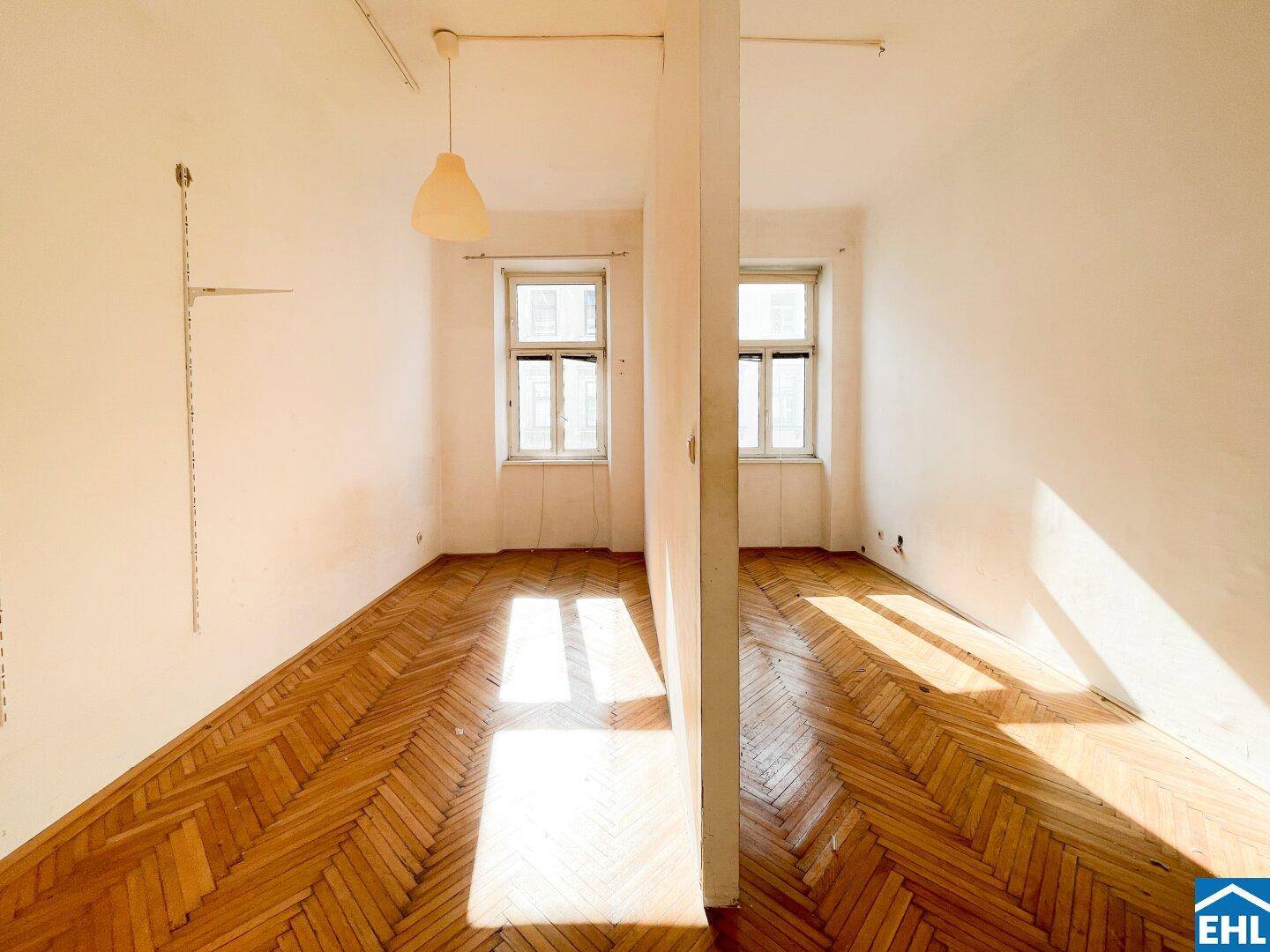 Helles Zimmer mit zwei Fenstern, Fischgrätparkettboden und viel natürlichem Lichteinfall.