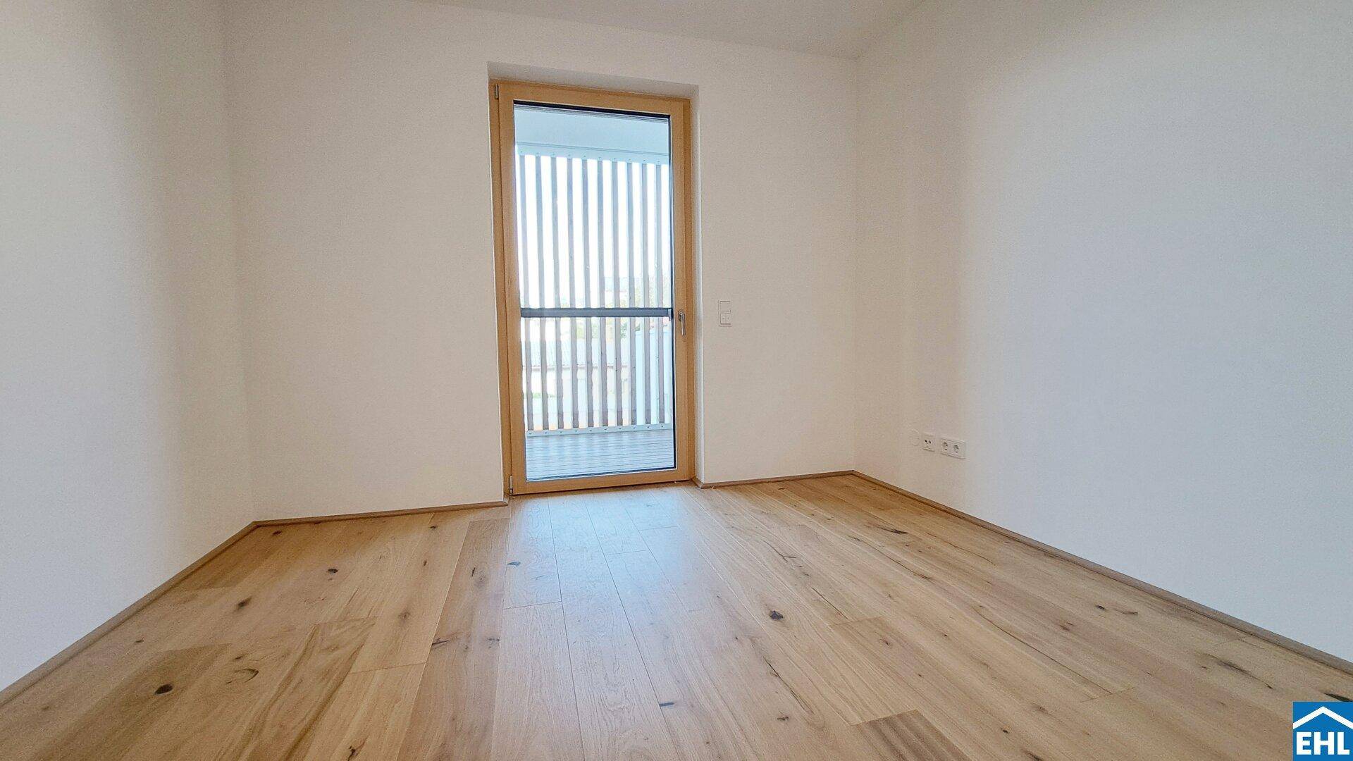 Lichtdurchflutetes Zimmer mit Holzboden und Zugang zum Balkon, perfekt für ein Schlafzimmer.