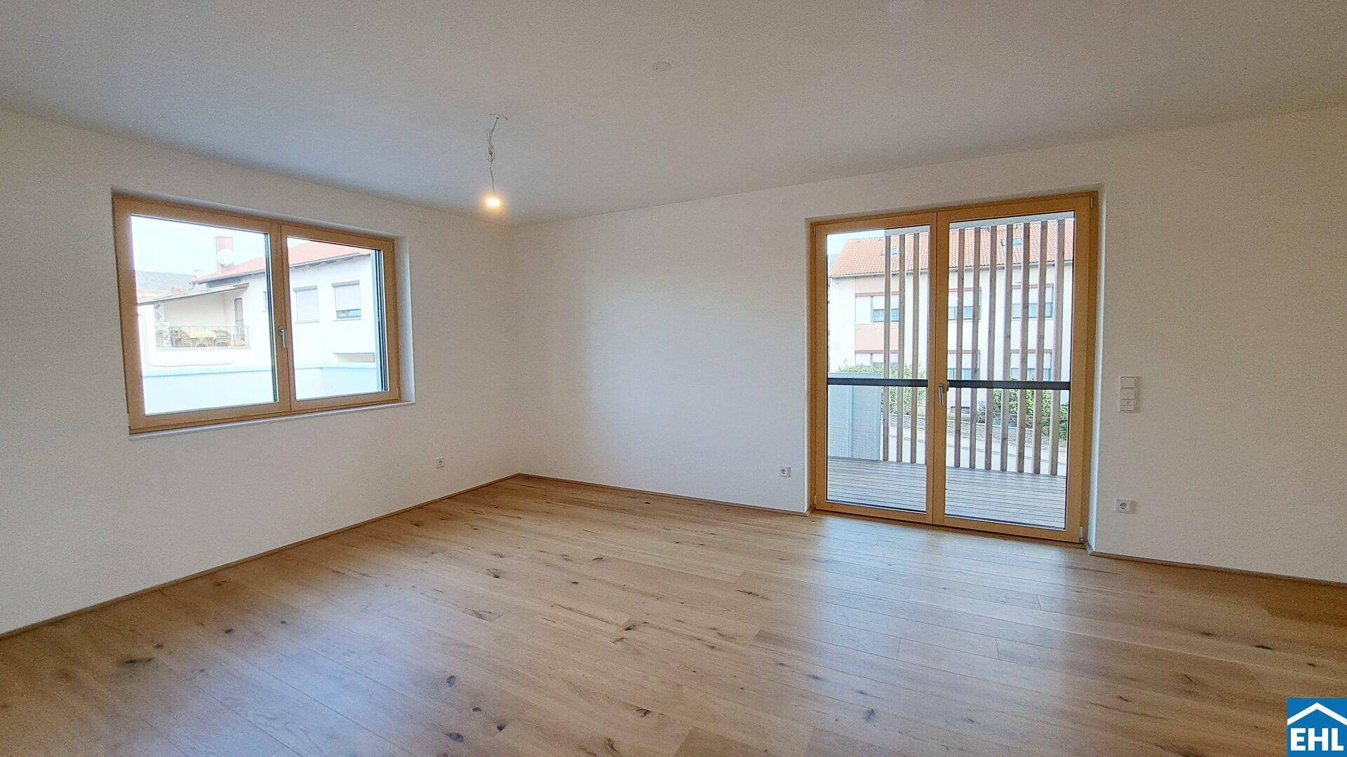 Geräumiges, helles Zimmer mit Holzboden, großen Fenstern und direktem Zugang zum Balkon.