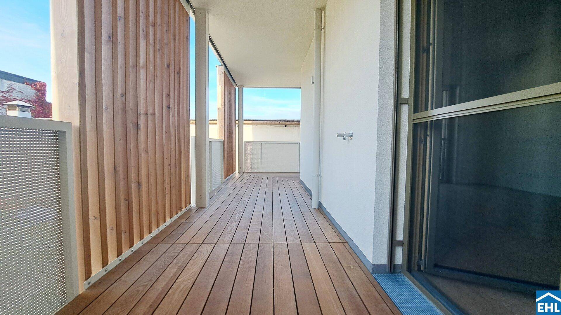 Geräumiger Balkon mit Holzboden und seitlichen Sichtschutzelementen.