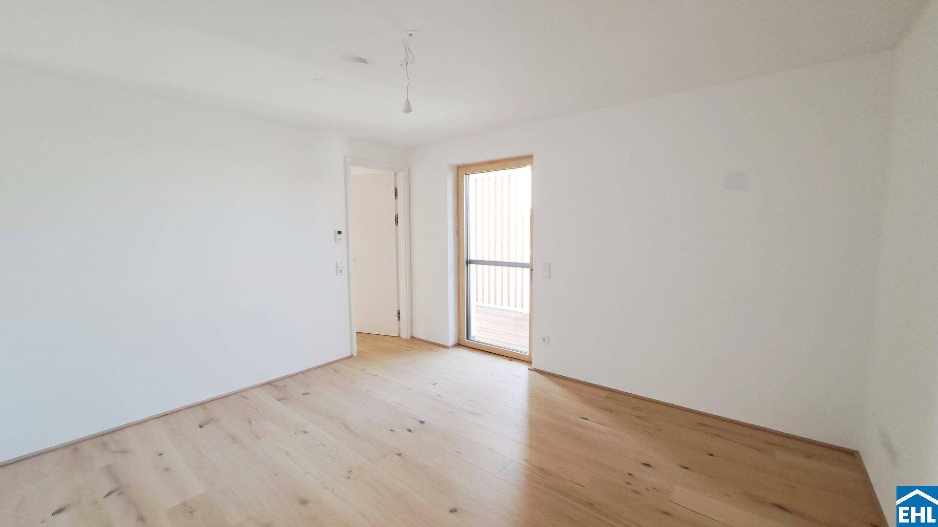 Lichtdurchflutetes Zimmer mit Holzboden und Zugang zum Balkon.