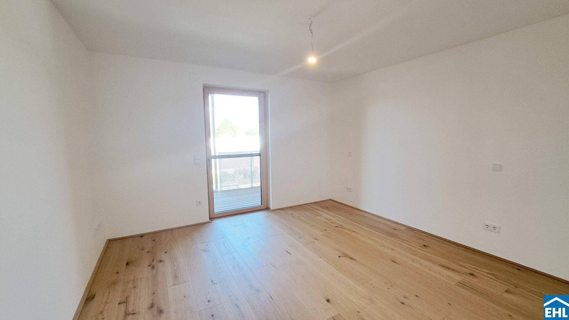Helles Zimmer mit Parkettboden und Zugang zu einem Außenbereich.
