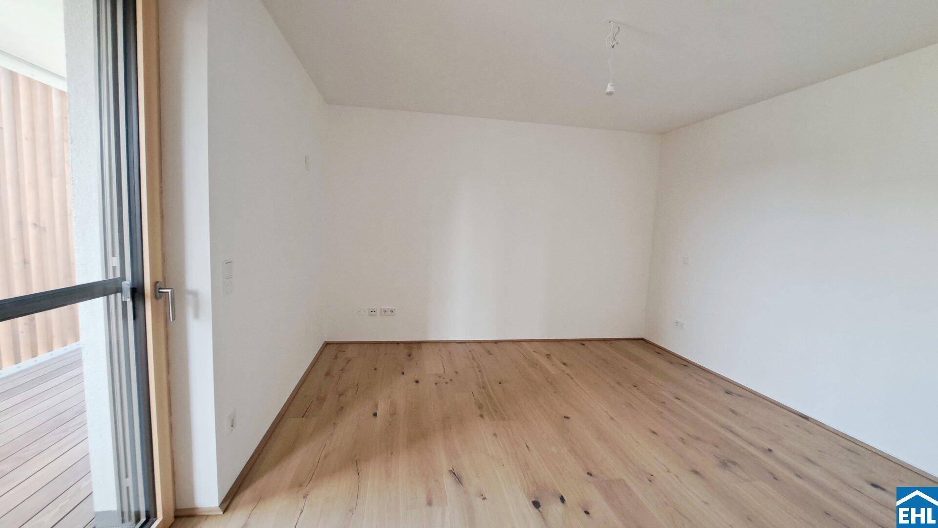 Heller Raum mit Parkettboden und direktem Zugang zur Holzterrasse.