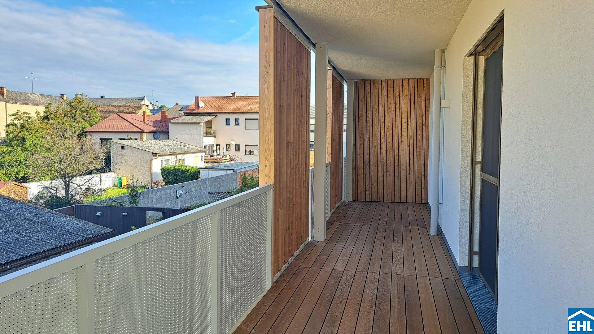 Langer Balkon mit Holzboden und Blick auf die umliegende Nachbarschaft.