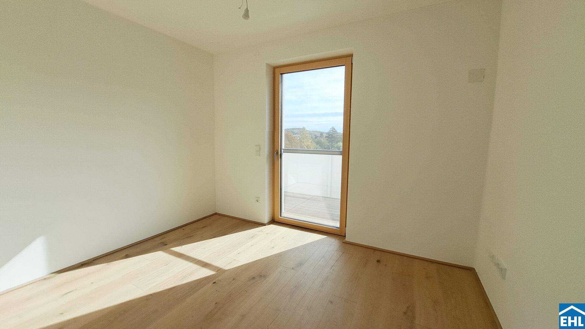 Helles Schlafzimmer mit Eichenparkett, weißen Wänden und direktem Zugang zu einem französischen Balkon.