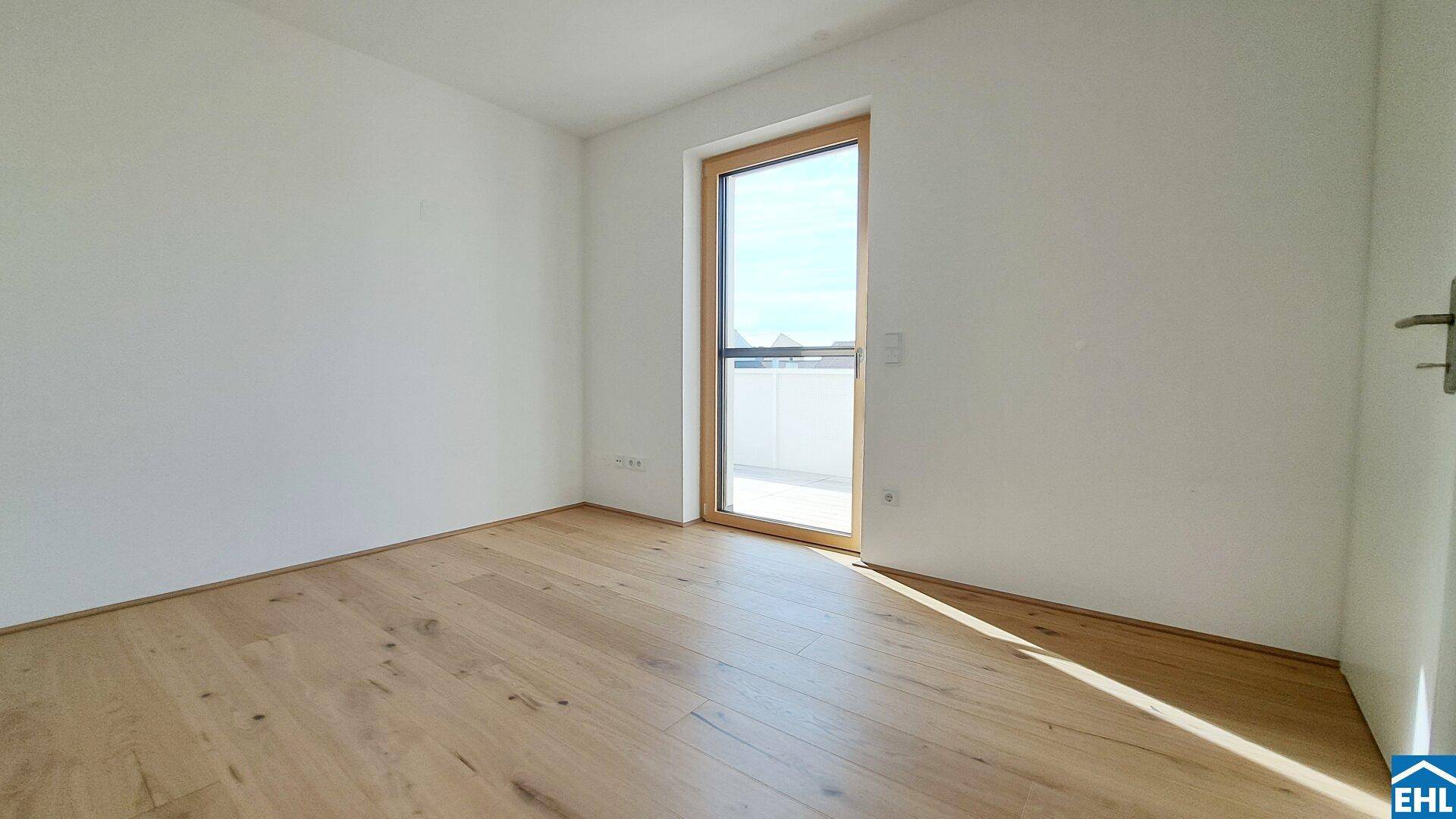 Lichtdurchflutetes Schlafzimmer mit hellem Parkettboden und großem Fenster, ideal für natürliche Belichtung.