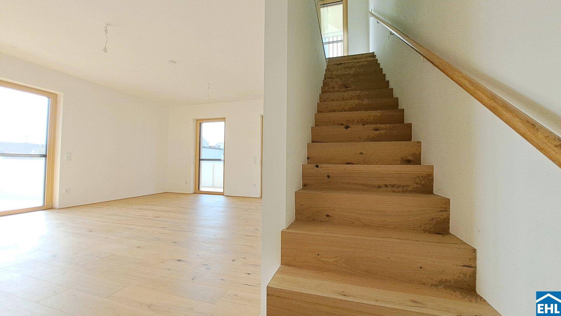 Moderne Holztreppe mit hellem Geländer, die die Etagen des Wohnraums elegant verbindet.