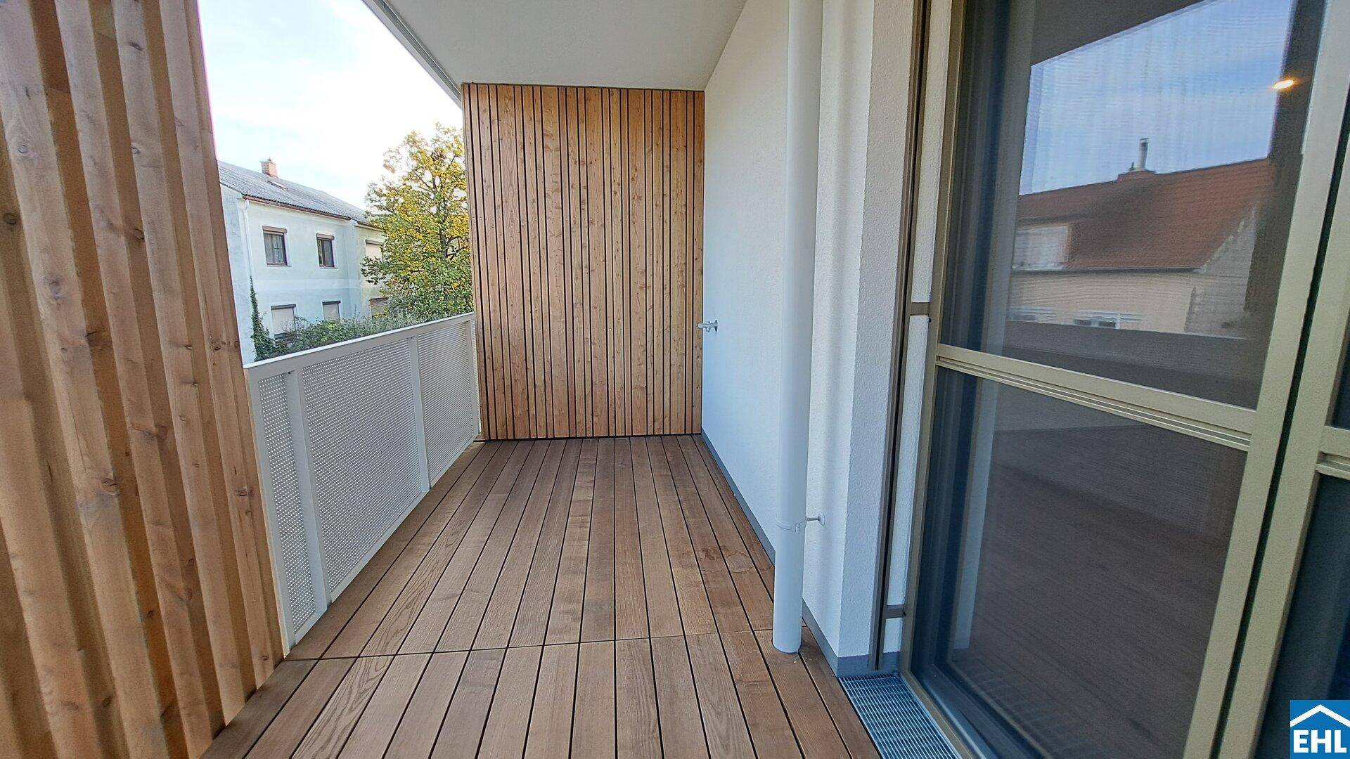 Geräumiger Balkon mit Holzbelag und moderner Holzverkleidung, ideal zum Entspannen.