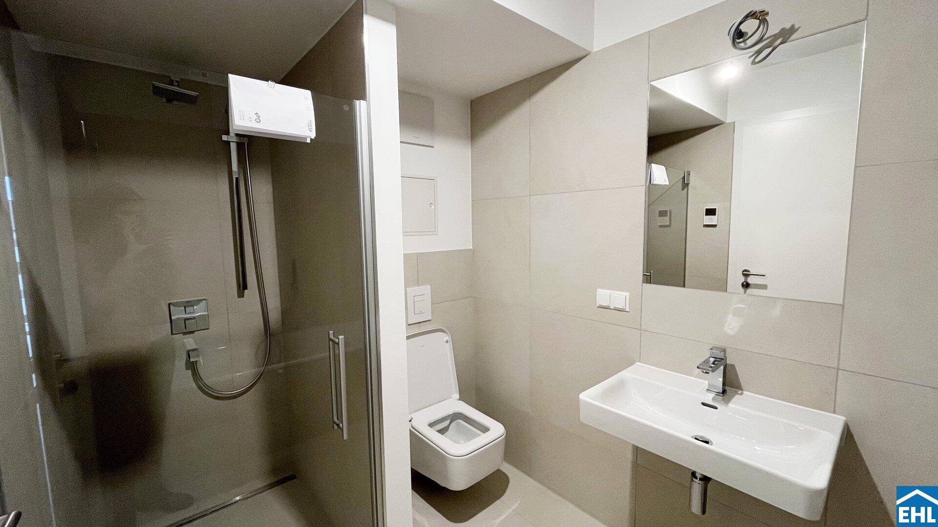 Modernes Badezimmer mit ebenerdiger Dusche, wandhängendem WC und Waschtisch mit Spiegelschrank.
