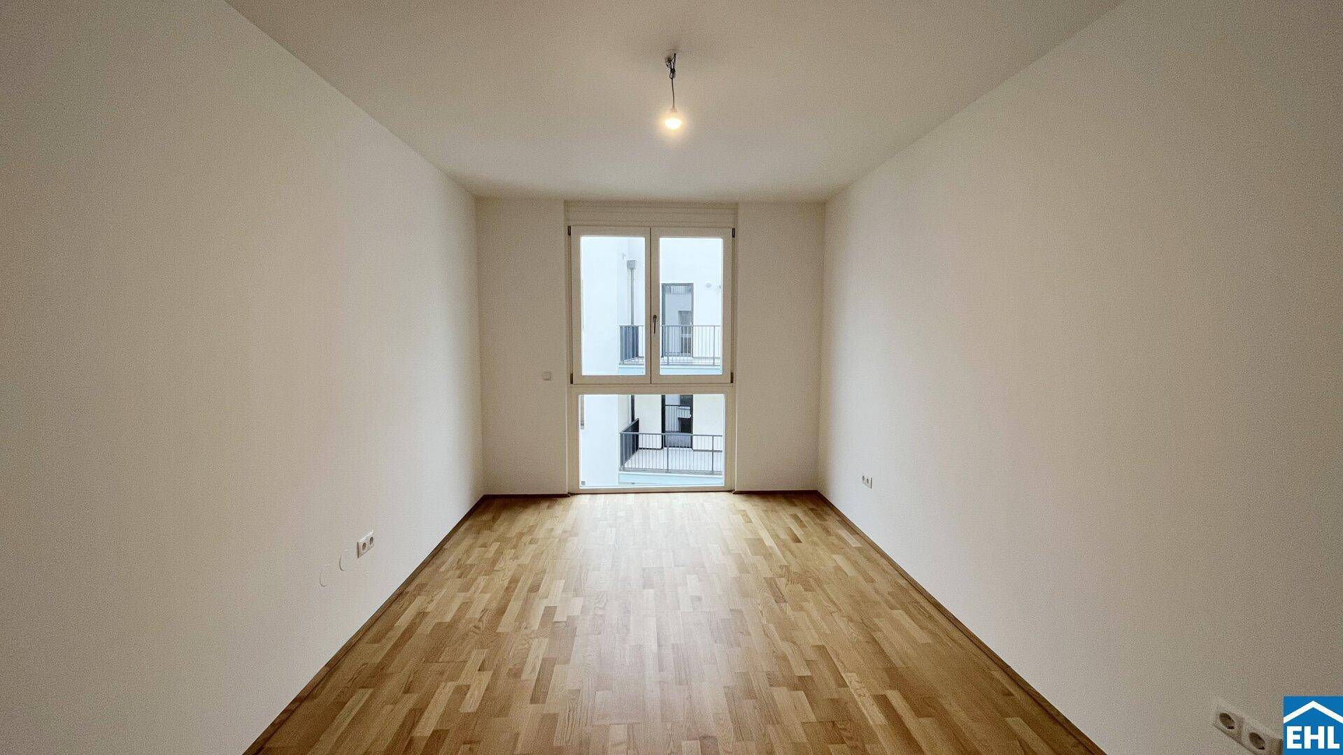Helles, unmöbliertes Schlafzimmer mit Holzboden und Zugang zu einem Balkon, bereit zur individuellen Gestaltung.