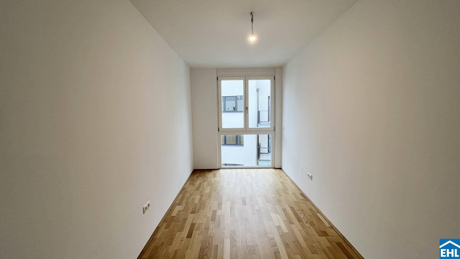 Helles, unmöbliertes Schlafzimmer mit Holzboden und Zugang zu einem Balkon, ideal für individuelle Gestaltung.