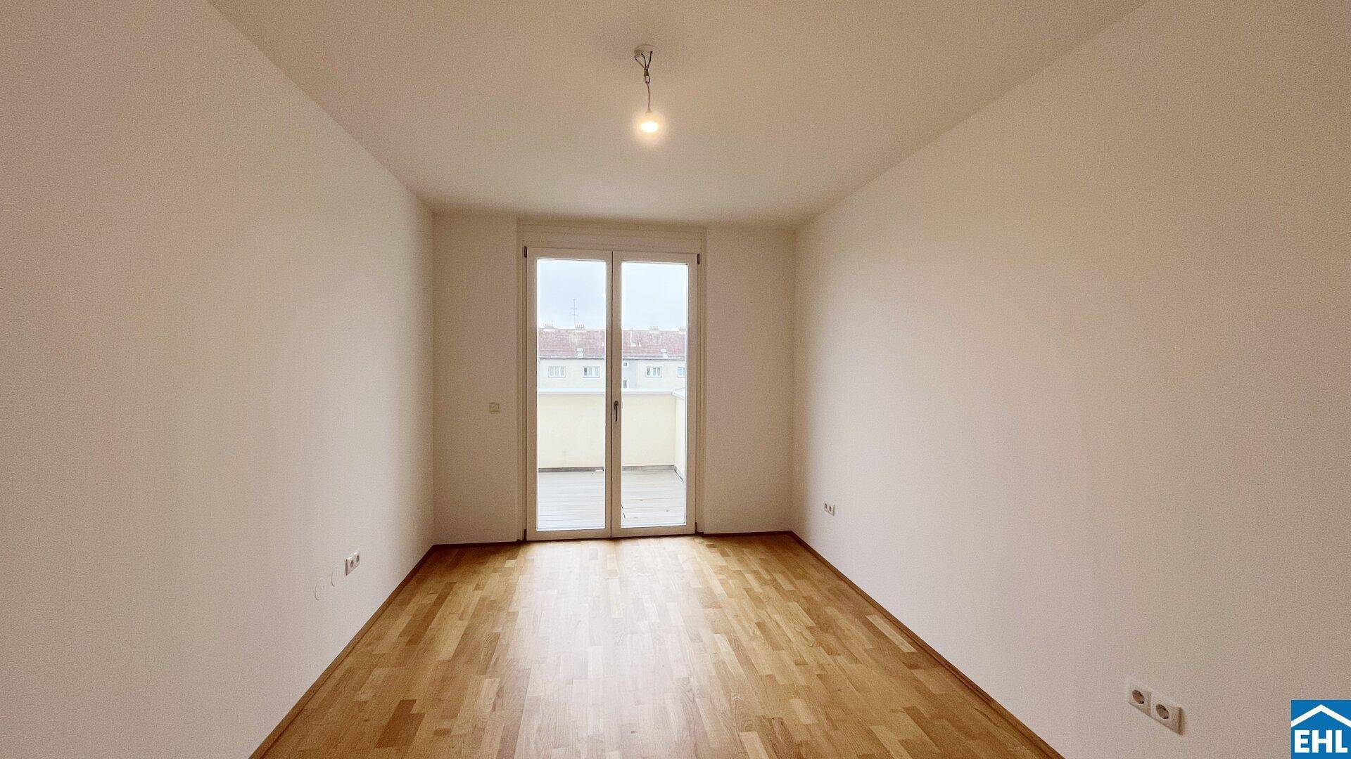 Unmöbliertes Schlafzimmer mit Parkettboden und Zugang zu einem französischen Balkon.