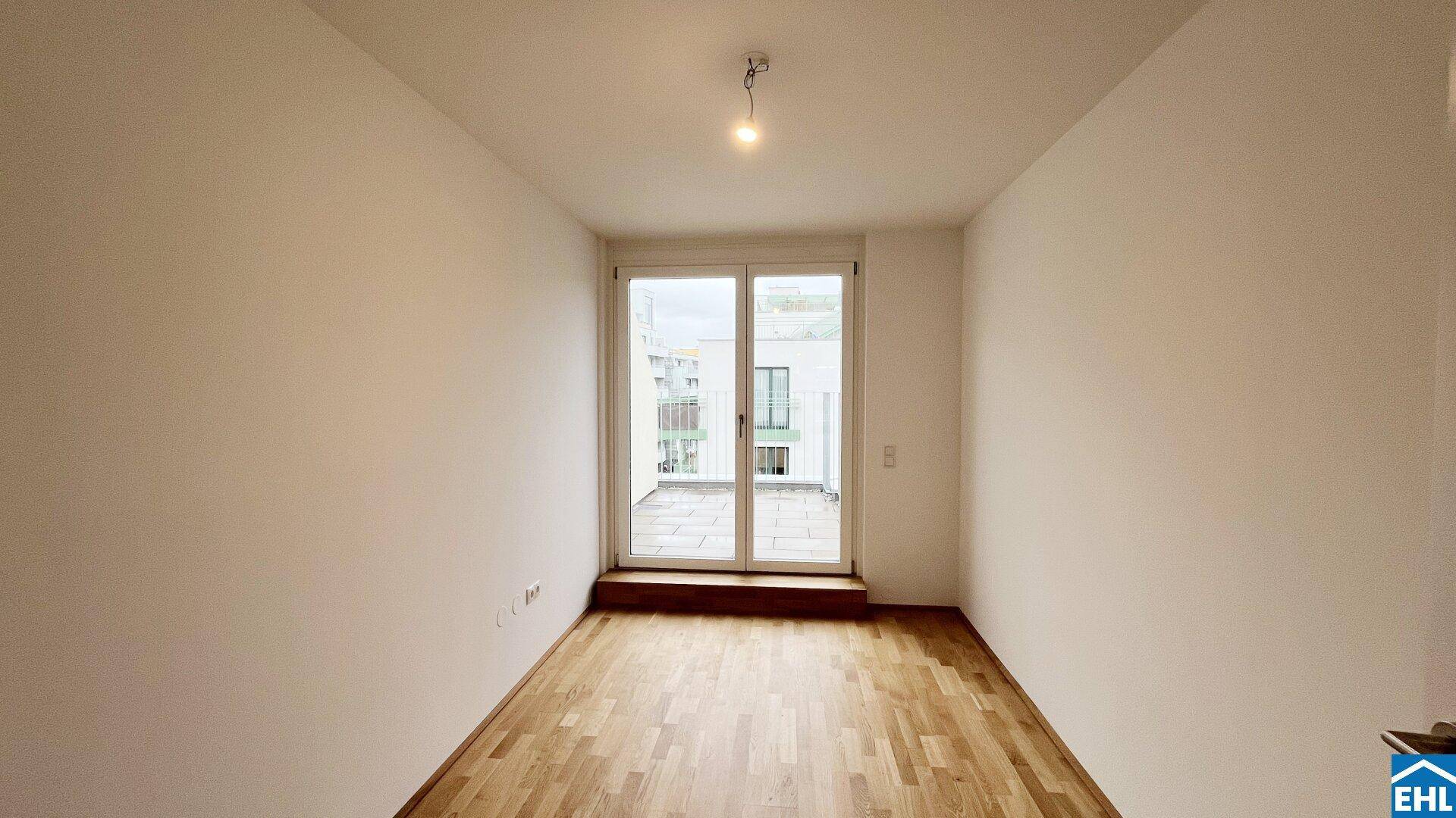 Helles Zimmer mit Holzboden und direktem Zugang zu einem gefliesten Außenbereich.