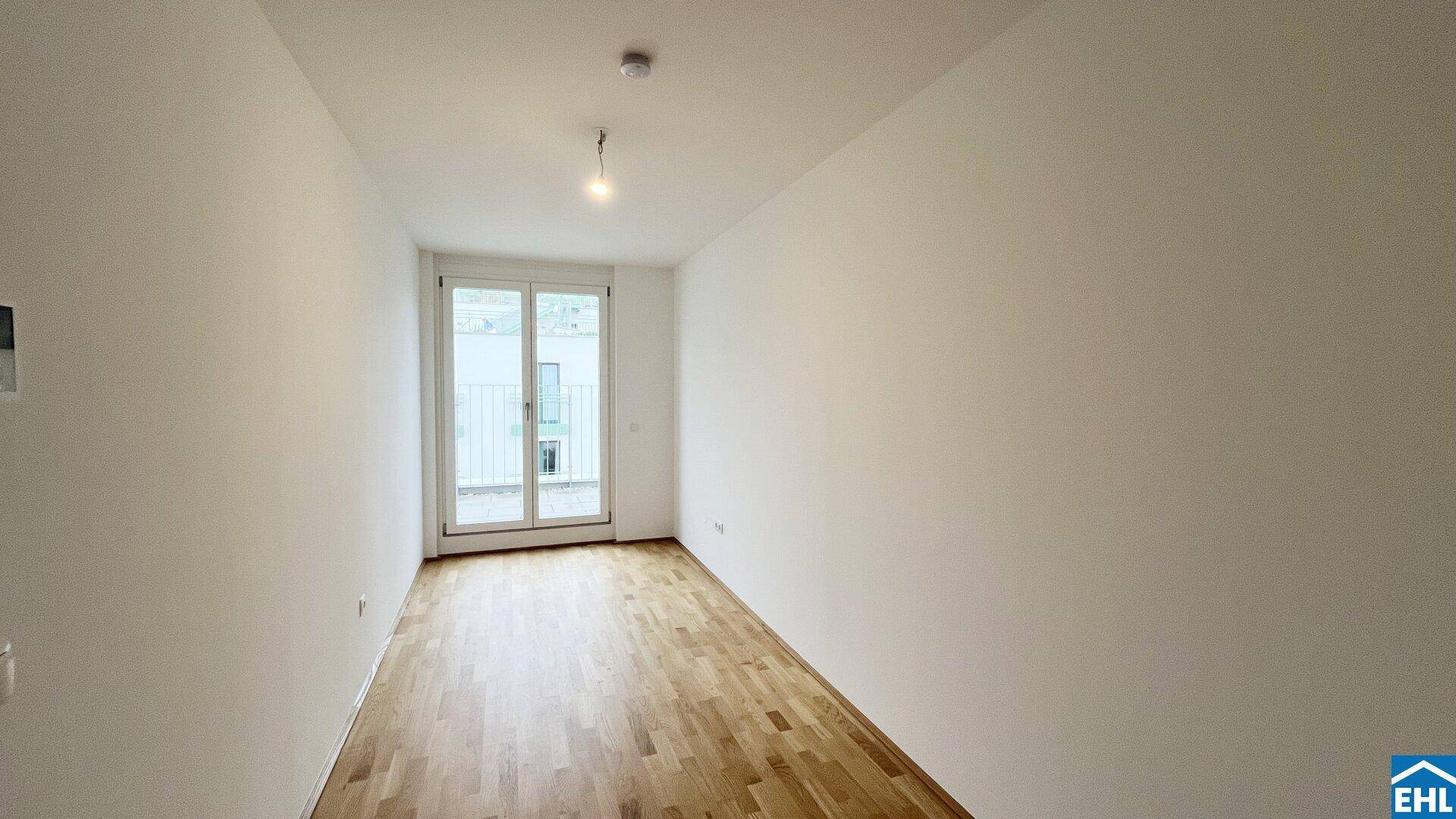 Leeres Schlafzimmer mit Parkettboden und Zugang zu einem kleinen Balkon, ideal für Ruhe.