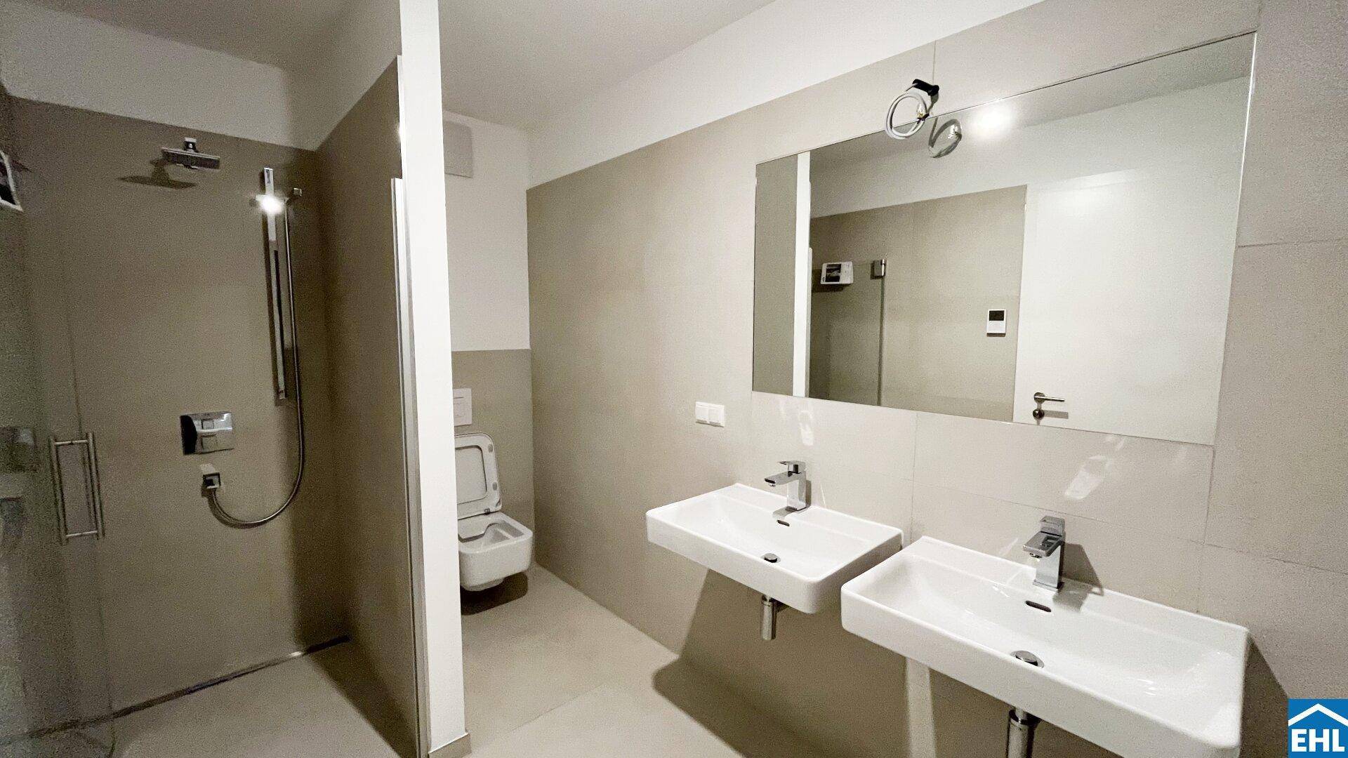 Modernes Badezimmer mit ebenerdiger Dusche, Doppelwaschbecken und Wand-WC in zeitlosem Design.