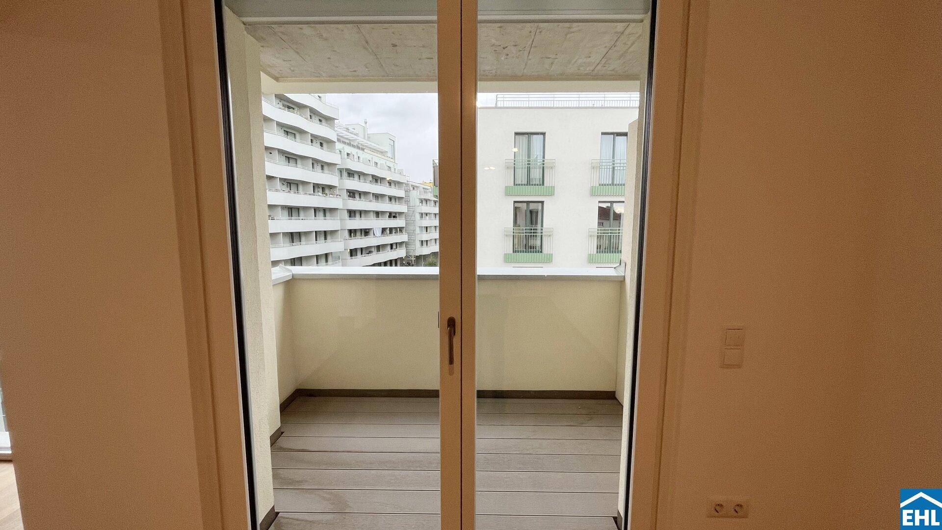 Leerer Balkon mit Holzboden und Blick auf die städtische Umgebung und andere Gebäude.