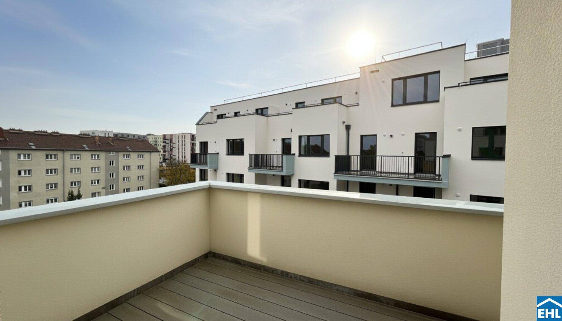 Geräumiger Balkon mit Holzboden und weitem Blick auf die umliegenden Gebäude und den Himmel.