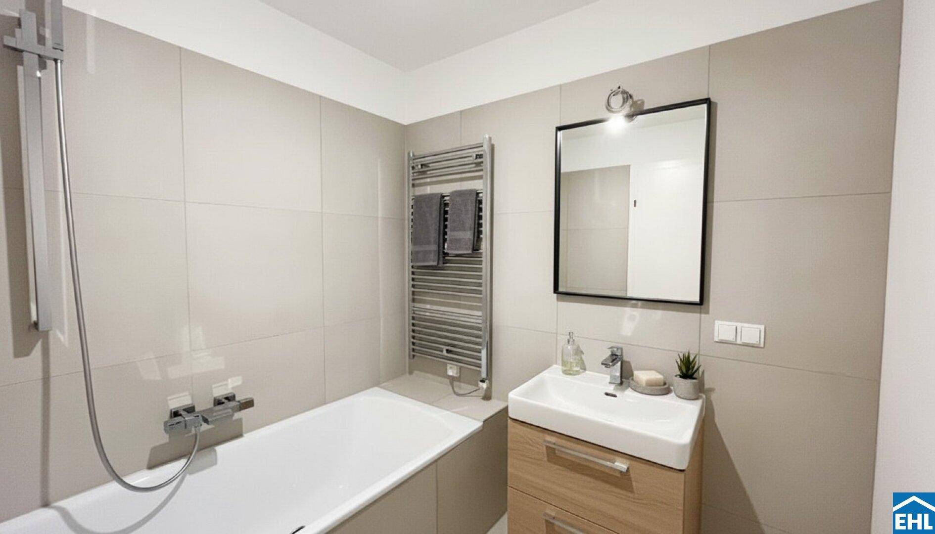Modernes Badezimmer mit Badewanne, Einzelwaschbecken und beheiztem Handtuchhalter, in hellen Farbtönen gehalten.