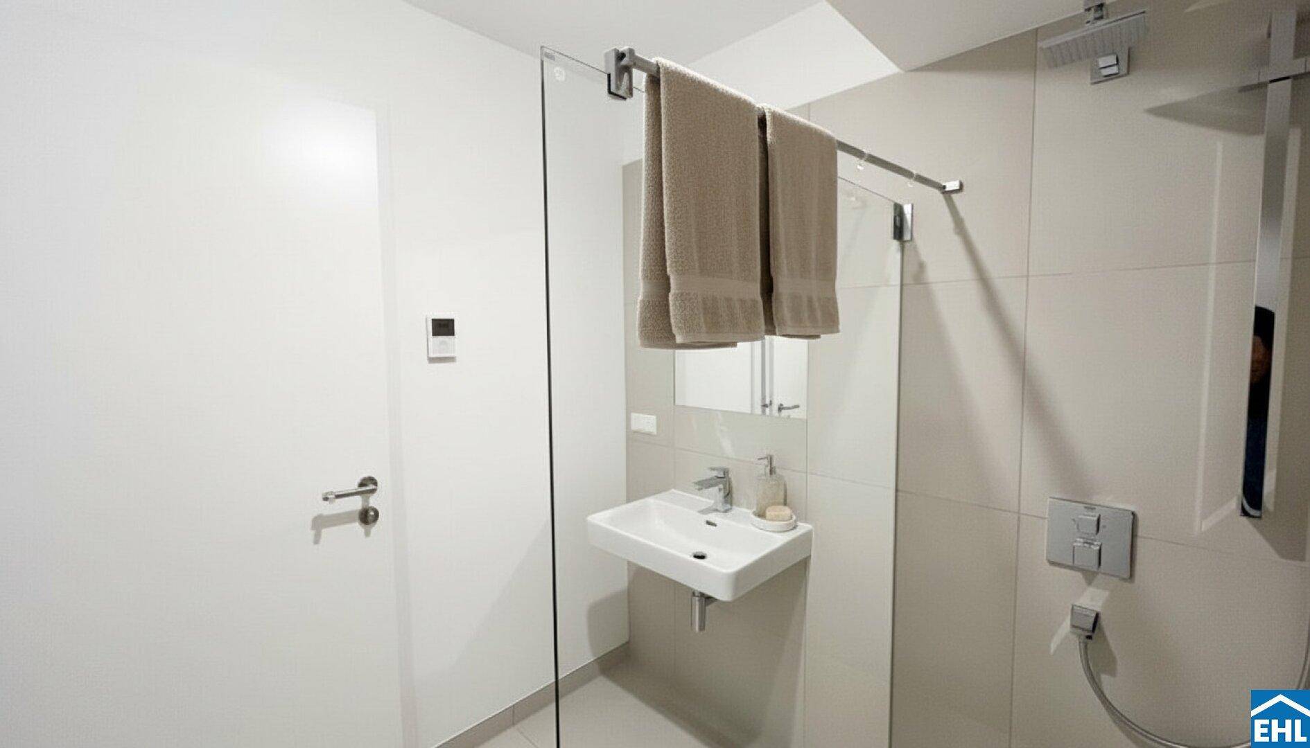Modernes Badezimmer mit begehbarer Dusche, Wandwaschbecken und hellen Fliesen.