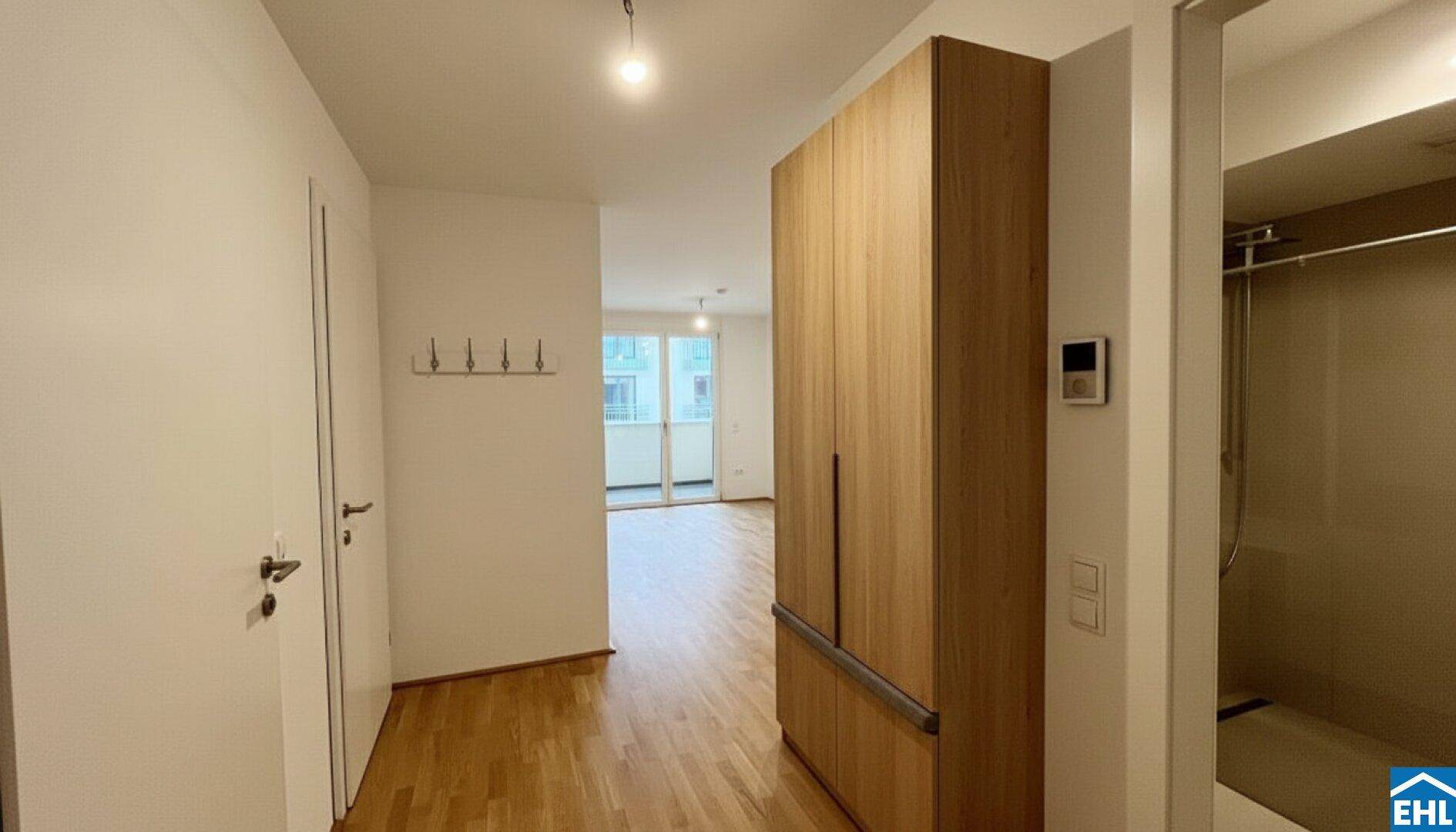 Eingangsbereich mit Holzboden, Garderobe und integriertem Schrank, führt zum Wohnbereich.