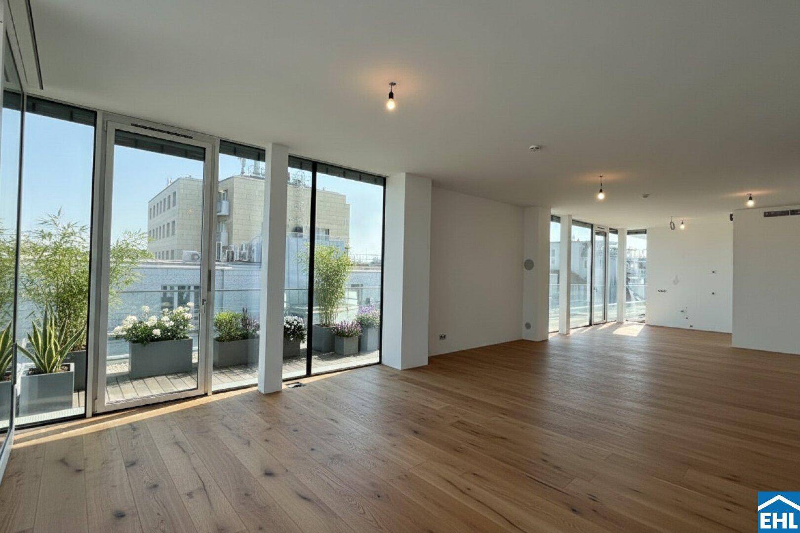 Geräumiger, leerer Wohnbereich mit Holzboden und großen Fenstern zur Terrasse.