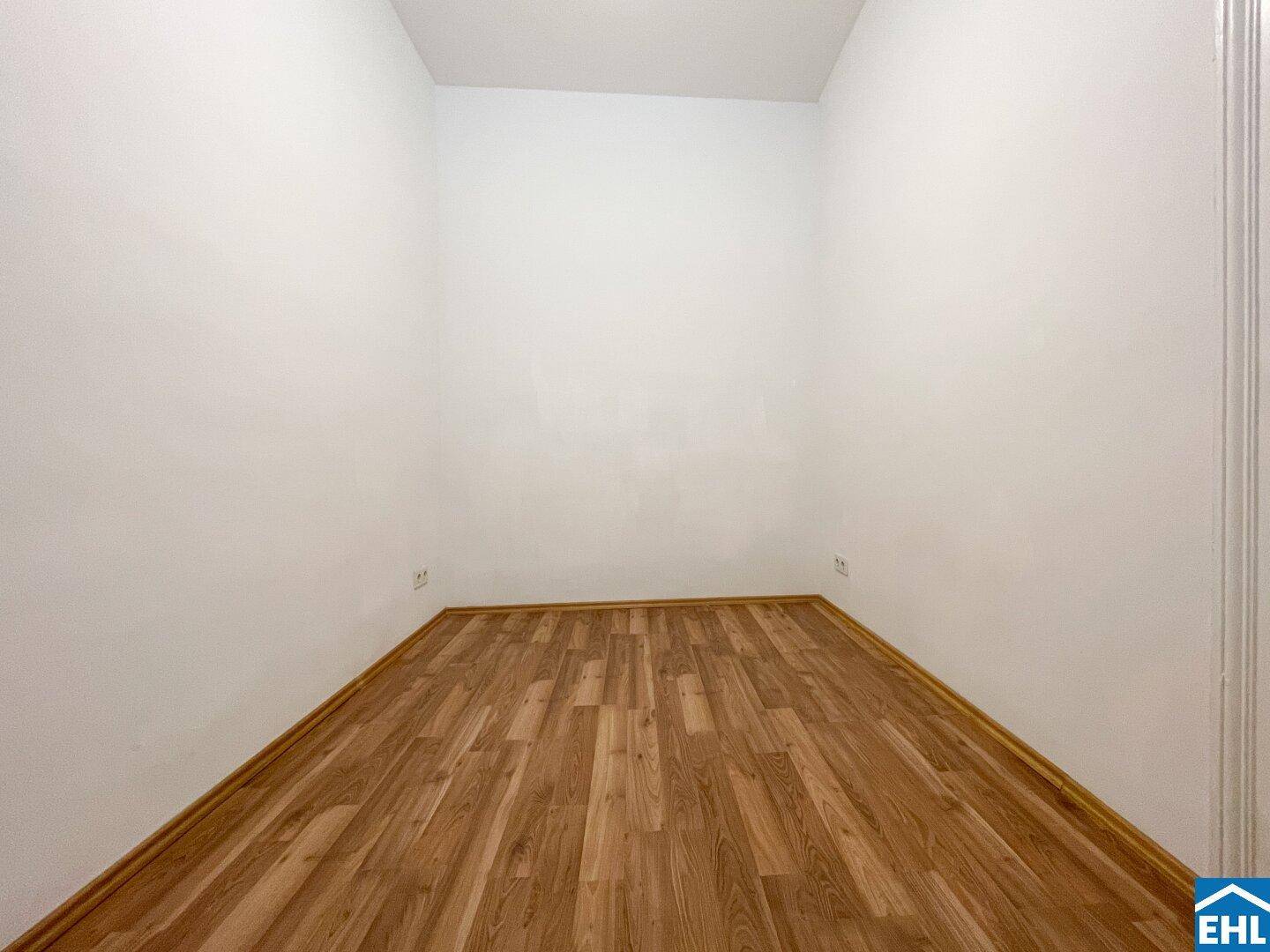 Leerer Raum mit Holzboden und weißen Wänden, bereit für individuelle Gestaltung.